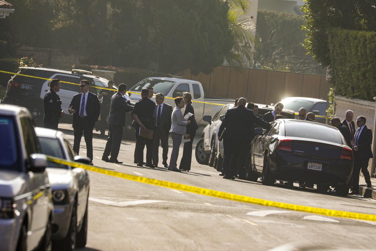 Law enforcement officials stand inside yellow crime scene tape.