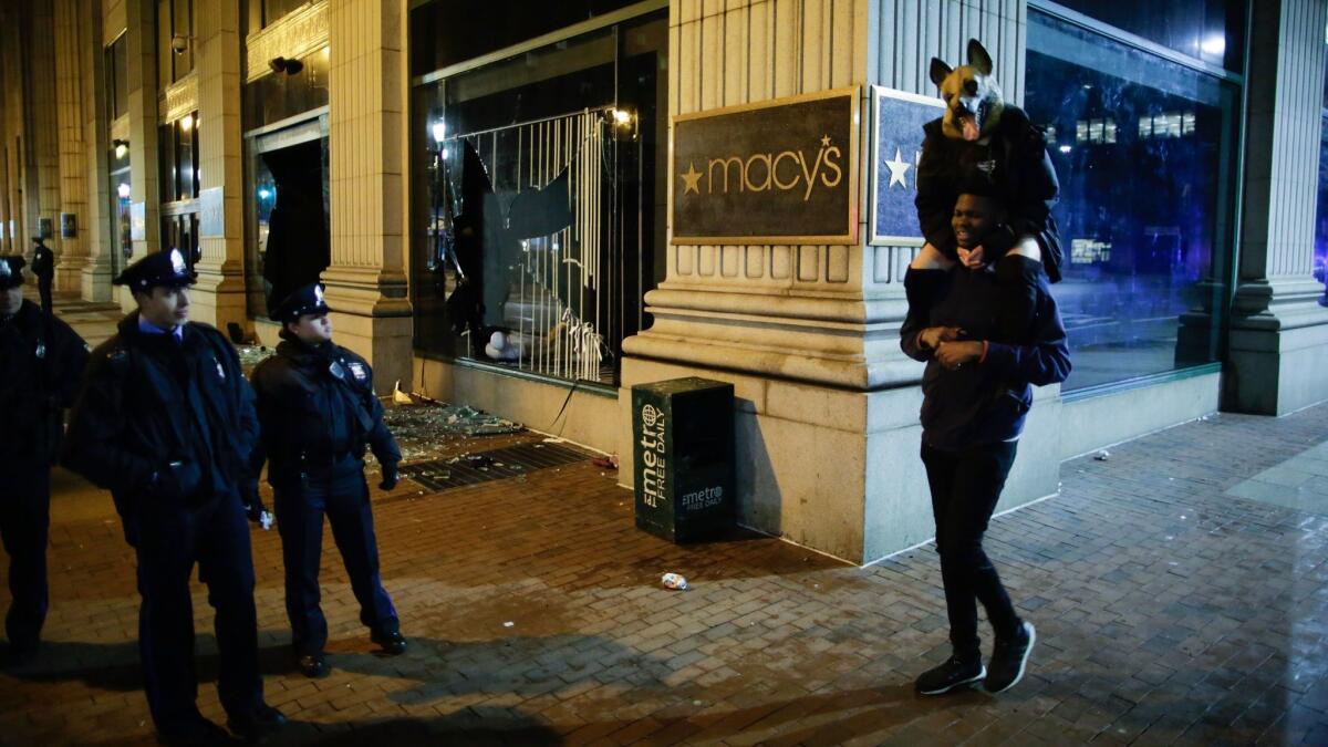 Philadelphia police officers try to keep fans away from broken Macy's store windows.