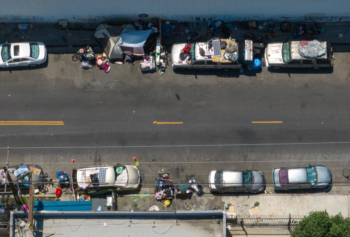 Cars line both sides of a road, with belongings on their roofs and spread nearby