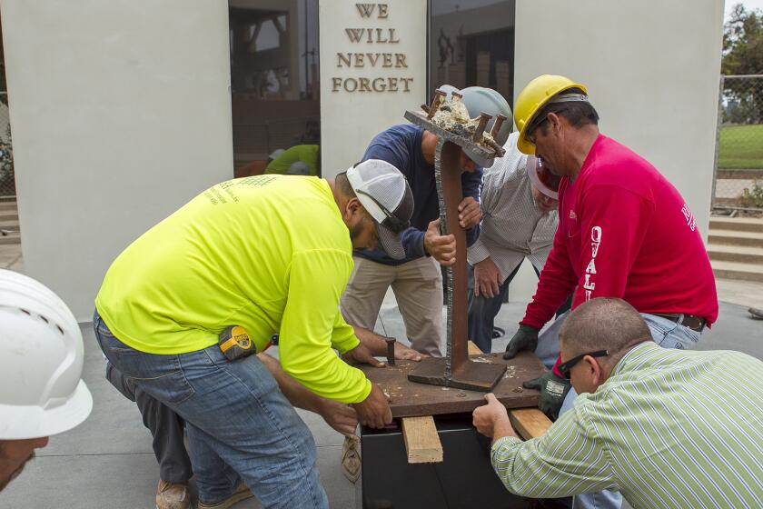 Employees with RBA Builders, Inc. work on the 9/11 memorial outside the Huntington Beach City Hall on Wednesday, Sept. 7, 2016.