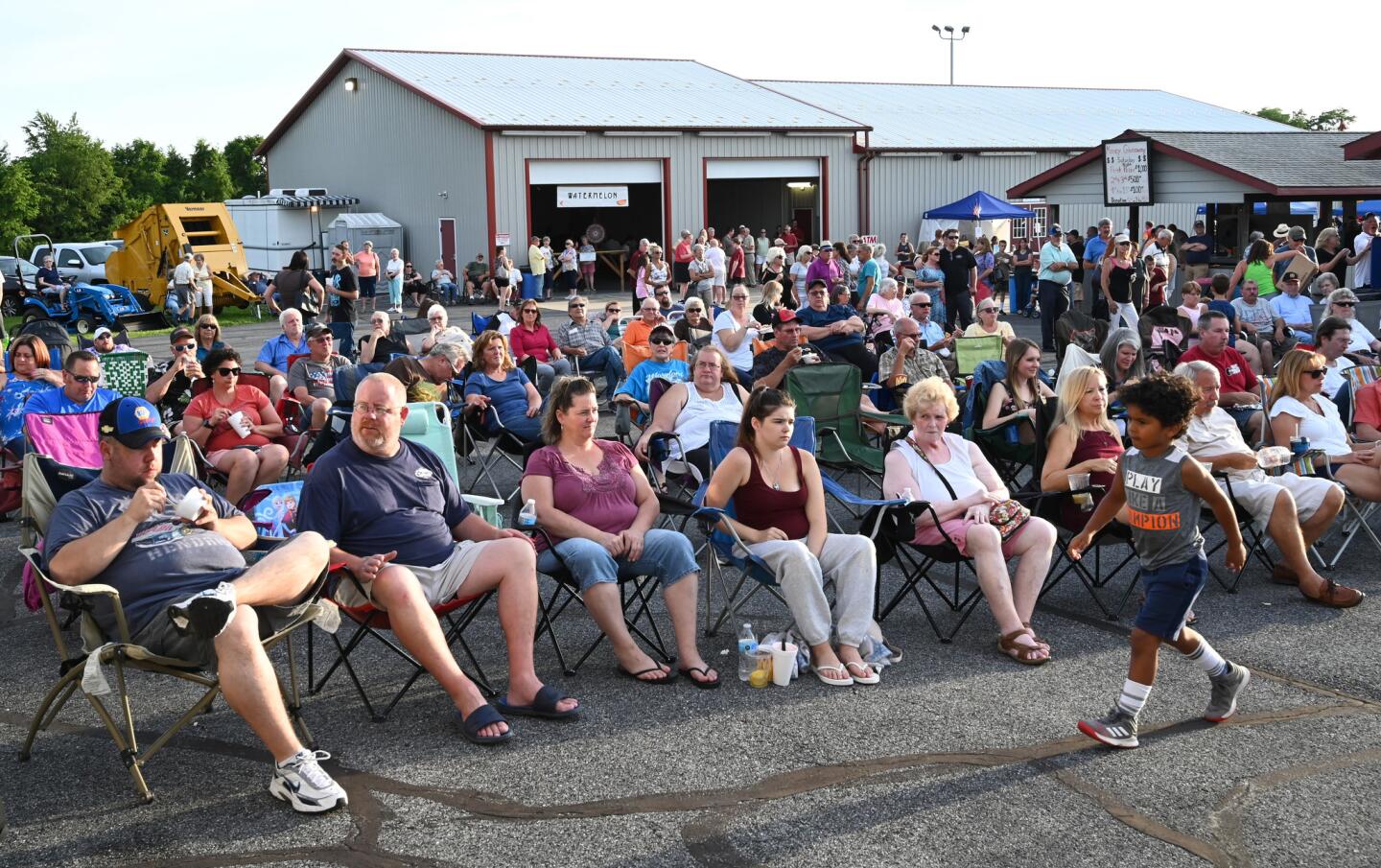 People relax in folding chairs, listening to the night's entertainment during the carnival at the Harney Volunteer Fire Company on Tuesday, June 25.