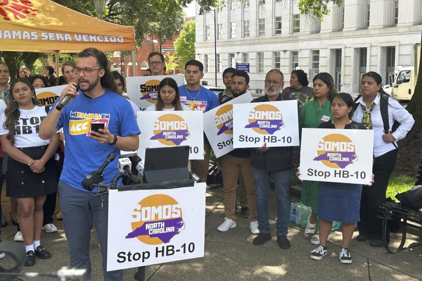 Axel Herrera Ramos, left, with Mi Familia en Acción in North Carolina, speaks at a rally outside the old state Capitol in Raleigh, N.C., involving advocates for the state's immigration community on Wednesday, May 1, 2024. Ramos and others spoke in opposition to a measure debated by the General Assembly that would force local sheriffs to comply with requests by federal agents interested in picking up jail inmates believed to be in the country illegally (AP Photo/Gary D. Robertson)