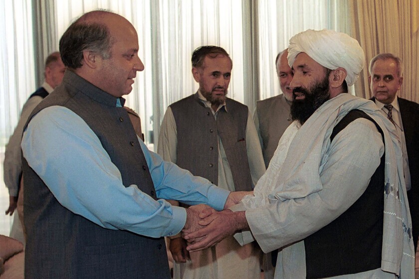 En esta imagen de archivo, el mulá Hassan Akhund (derecha), entonces ministro de Exteriores de Afganistán, es recibido por el primer ministro de Pakistán, Nawaz Sharif, en Islamabad, el 25 de agosto de 1999. (AP Foto/B.K. Bangash, archivo)