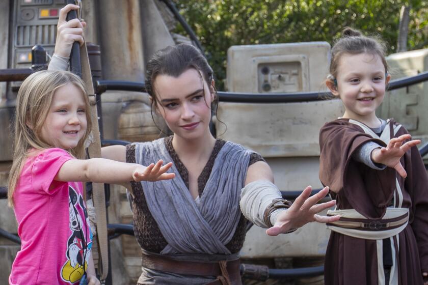 ANAHEIM, CALIF. -- THURSDAY, JANUARY 16, 2020: A cast member dressed as Rey poses for a photo with Penny Remaklus, 4, left, and Adelaide Remaklus, 7, of Ferndale, Washington, during media preview of Star Wars: Rise of the Resistance Media Preview at the Disneyland Resort in Anaheim, Calif., on Jan. 16, 2020. Star Wars: Galaxy's Edge (Allen J. Schaben / Los Angeles Times)