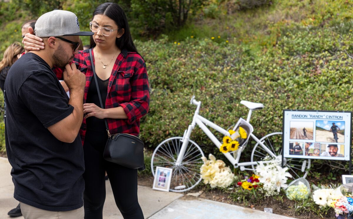 Richard Cintron, brother of Randy Cintron, receives comfort from Nicolina Trejo at the ghost bike memorial.