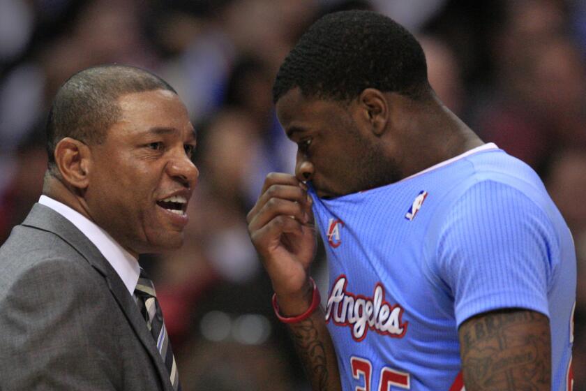 Clippers Coach Doc Rivers, left, speaks with guard Reggie Bullock during a game against the Chicago Bulls in November. Bullock has had soreness in his right leg and will not play in the NBA summer league.