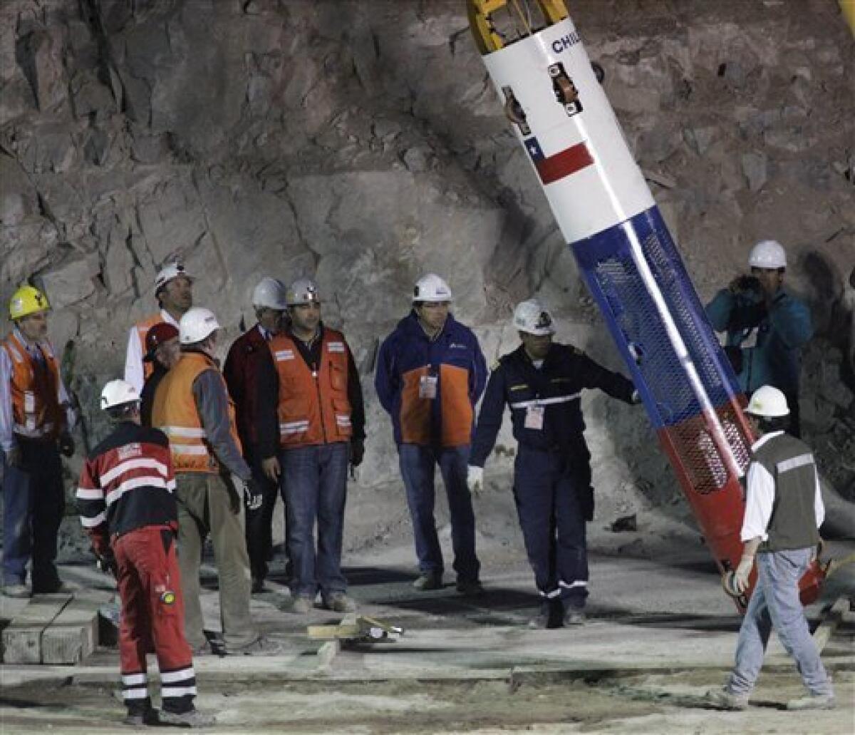 Rescue workers and officials test the rescue capsule that will be used to extract the 33 trapped miners one by one at the San Jose Mine near Copiapo, Chile, Tuesday Oct. 12, 2010. The first of 33 trapped miners is expected to be lifted to the surface late Tuesday after surviving more than two months below ground. (AP Photo/Jorge Saenz)
