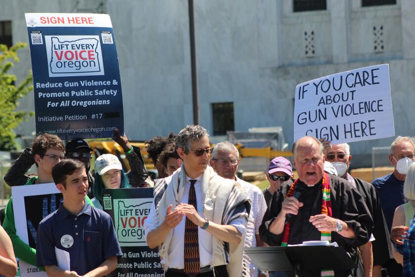 FILE -Rev. Mark Knutson, right, chief petitioner of a gun initiative, speaks at a rally, joined by Rabbi Michael Cahana, center, outside the Oregon State Capitol in Salem before signatures are delivered to Oregon elections officials to get the proposal on the ballot on July 8, 2022. Oregonians will decide in November whether people wanting to purchase a gun will first have to qualify for a permit, after one of the strictest gun-control measures in the nation was approved to get on the ballot. (AP Photo/Andrew Selsky,File)