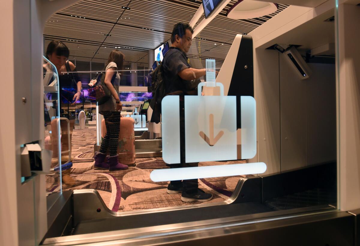 Passengers check in their luggage using an automated booth at the newly opened Terminal 4 at Changi International Airport.