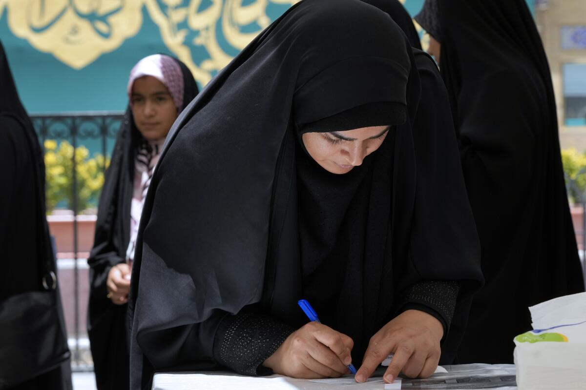 A woman fills out her ballot during the Iranian presidential election.