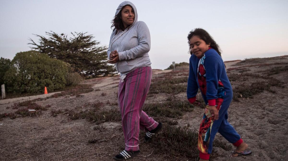 Kelly Ramirez, 17, left, and her sister Briseyda Sandoval, 6, walk along the dunes from their campground at Doran Regional Park in Bodega Bay. Their family is camping at the park to escape the smoke inundating their home in Windsor.