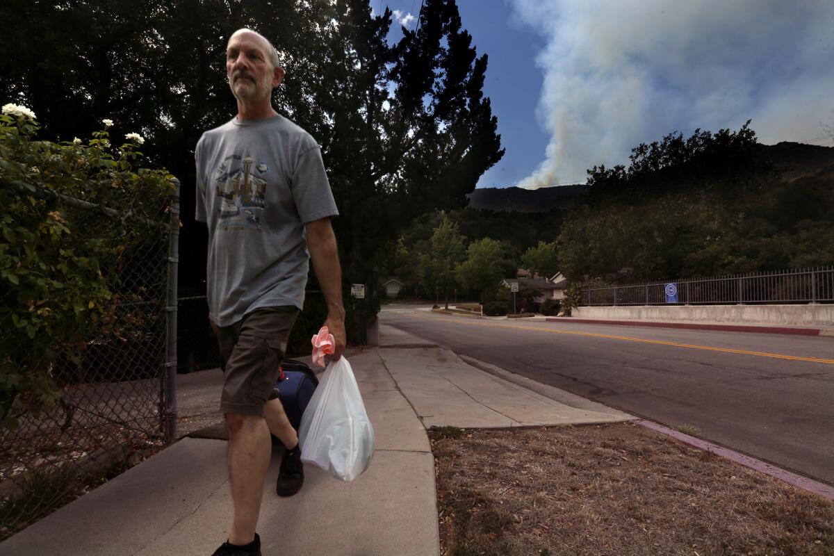 Gregory Lasavio evacuates the Glenwood Oaks community as the La Tuna fire rages in the Verdugo Mountains.