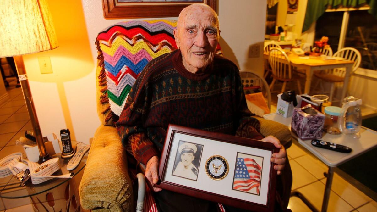 Veteran Carl Morgan holds a picture of himself when he was in the Navy during World War II as he gets ready to go out on his Holiday Lights and Limos tour.