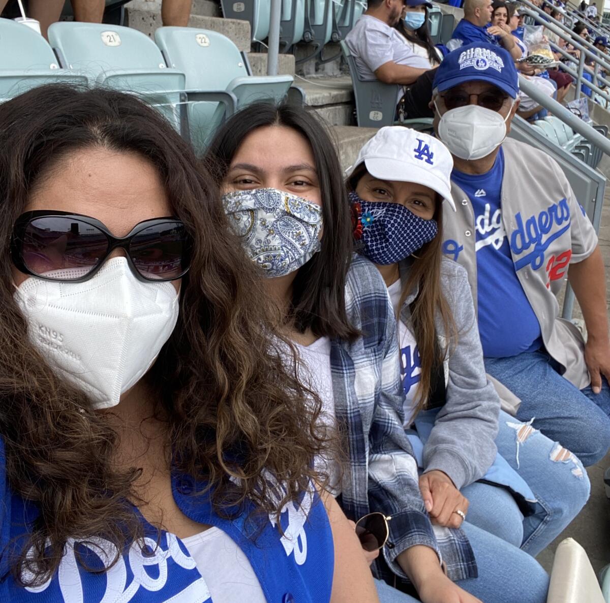 Four people in team shirts and colors pose for a selfie at Dodger Stadium