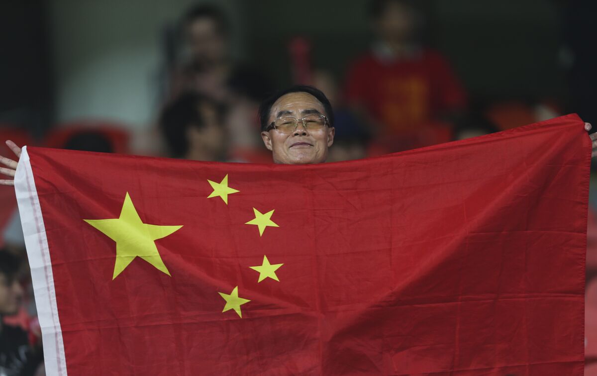 FILE - China's fan holds national flag before the AFC Asian Cup quarterfinal soccer match between Iran and China at Mohammed Bin Zayed Stadium in Abu Dhabi, United Arab Emirates, on Jan. 24, 2019. China withdrew as host of soccer's 2023 Asian Cup on Saturday, May 14, 2022, in the latest cancellation of the country's sports hosting duties during the COVID-19 pandemic. (AP Photo/Kamran Jebreili, File)