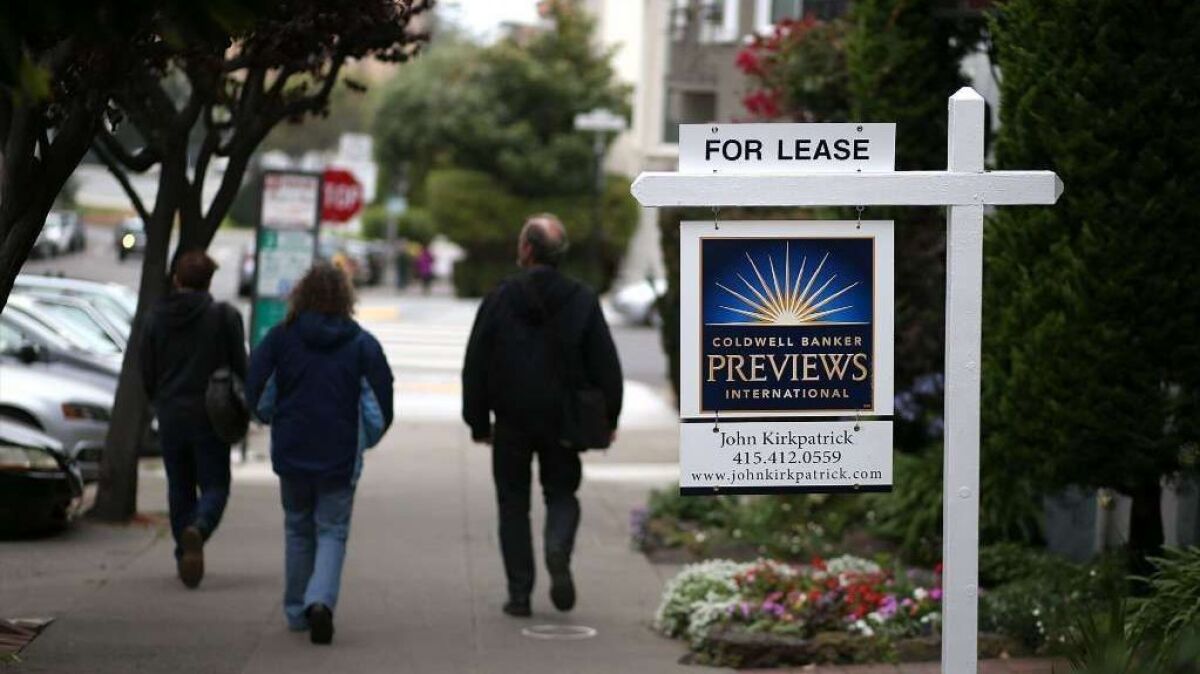 Pedestrians walk by a for lease sign in San Francisco in 2015.