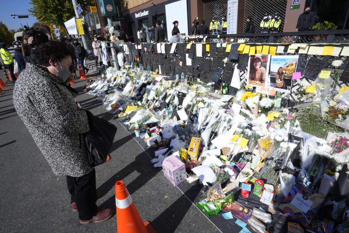 A woman wipes her tears as she pays tribute to victims of a deadly accident that happened during Saturday night's Halloween festivities, at a makeshift flower-laying area set up near the scene of the accident in Seoul, South Korea, Wednesday, Nov. 2, 2022. South Korean officials admitted responsibility and apologized on Tuesday for failures in preventing and responding to a Halloween crowd surge that killed more than 150 people and left citizens shocked and angry. (AP Photo/Ahn Young-joon)