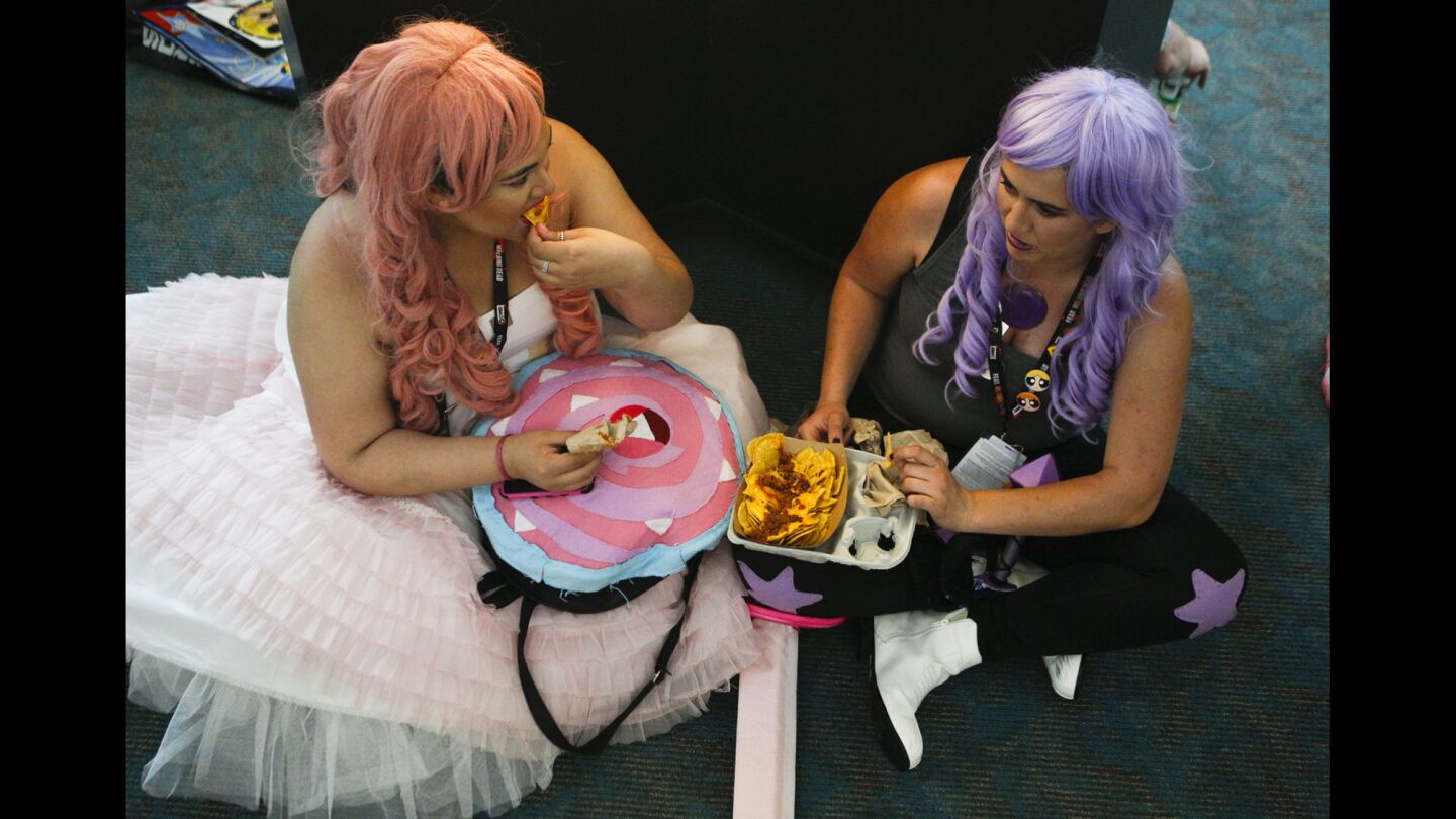 Bay Area residents Lex Lopez, left, and Kaitlin Brawley relax and eat nachos during the second day of Comic-Con.