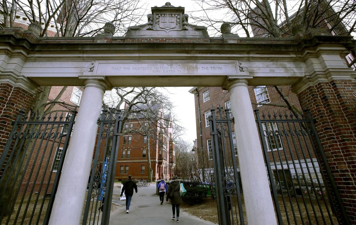 ARCHIVO - Algunos estudiantes ingresan por una puerta de la Universidad de Harvard 