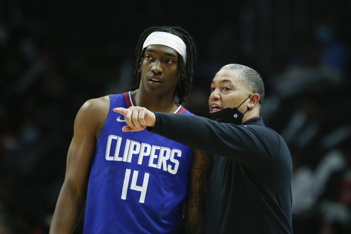 Clippers coach Tyronn Lue talks strategy with guard Terance Mann along the sideline during a break in play.