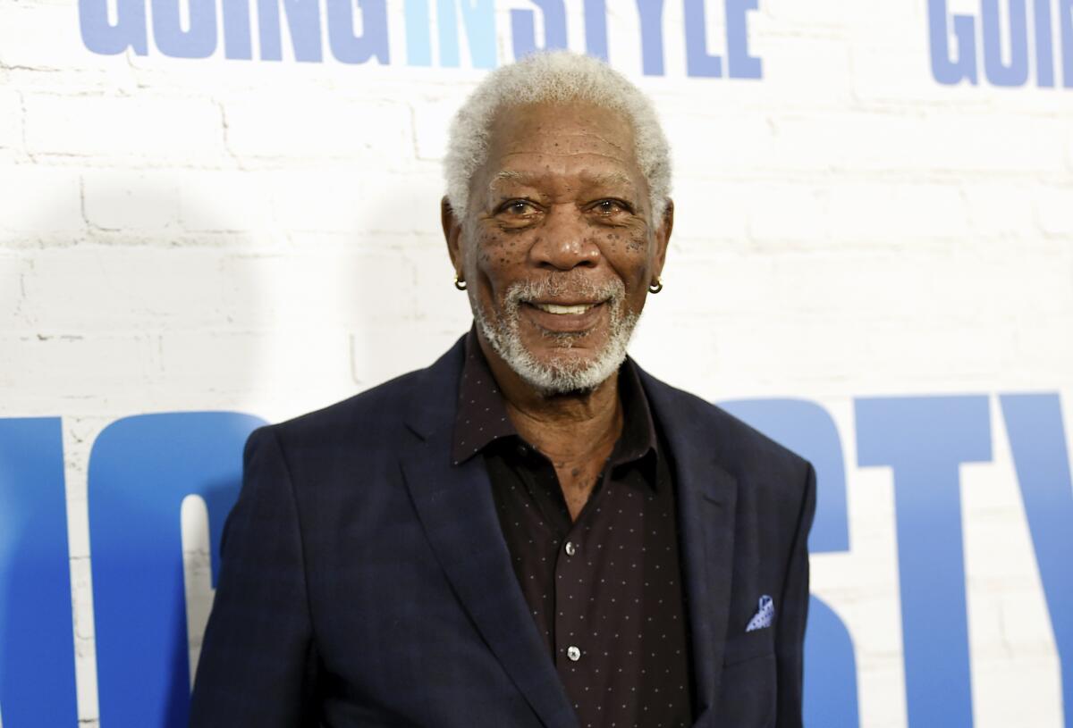 Morgan Freeman smiles in a dark suit against a white background