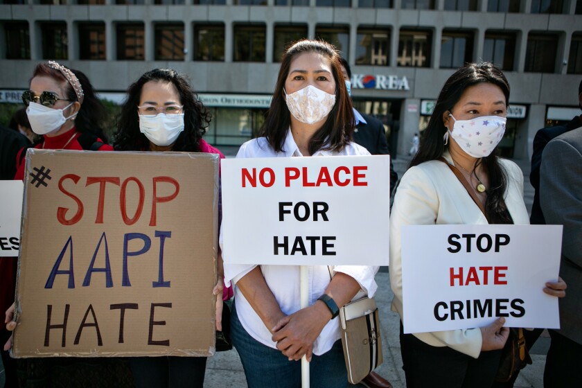 Three women with signs that say Stop AAPI Hate, No Place for Hate, and Stop Hate Crimes