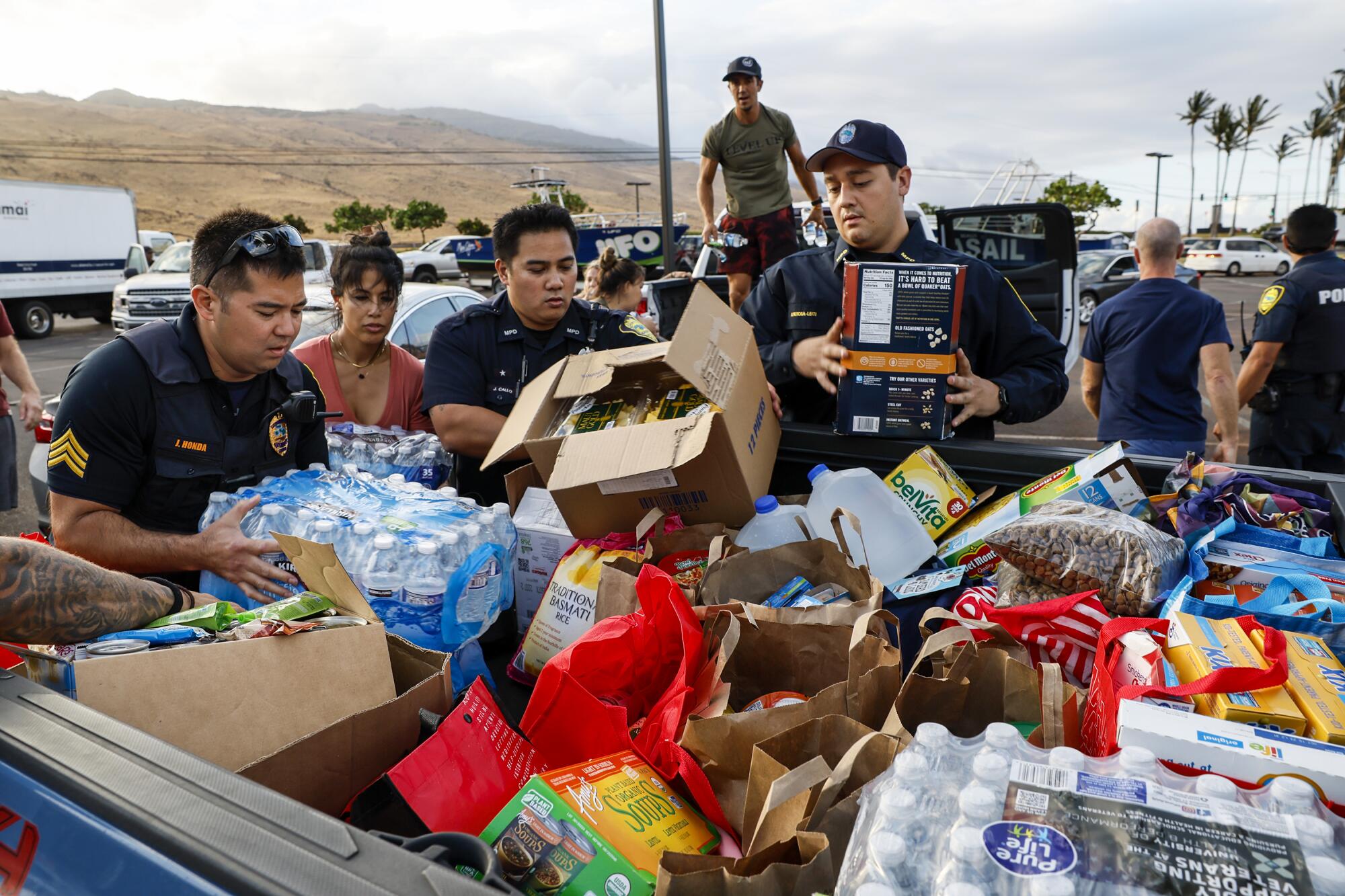 Maui police officers help pack truckloads of food and supplies. 