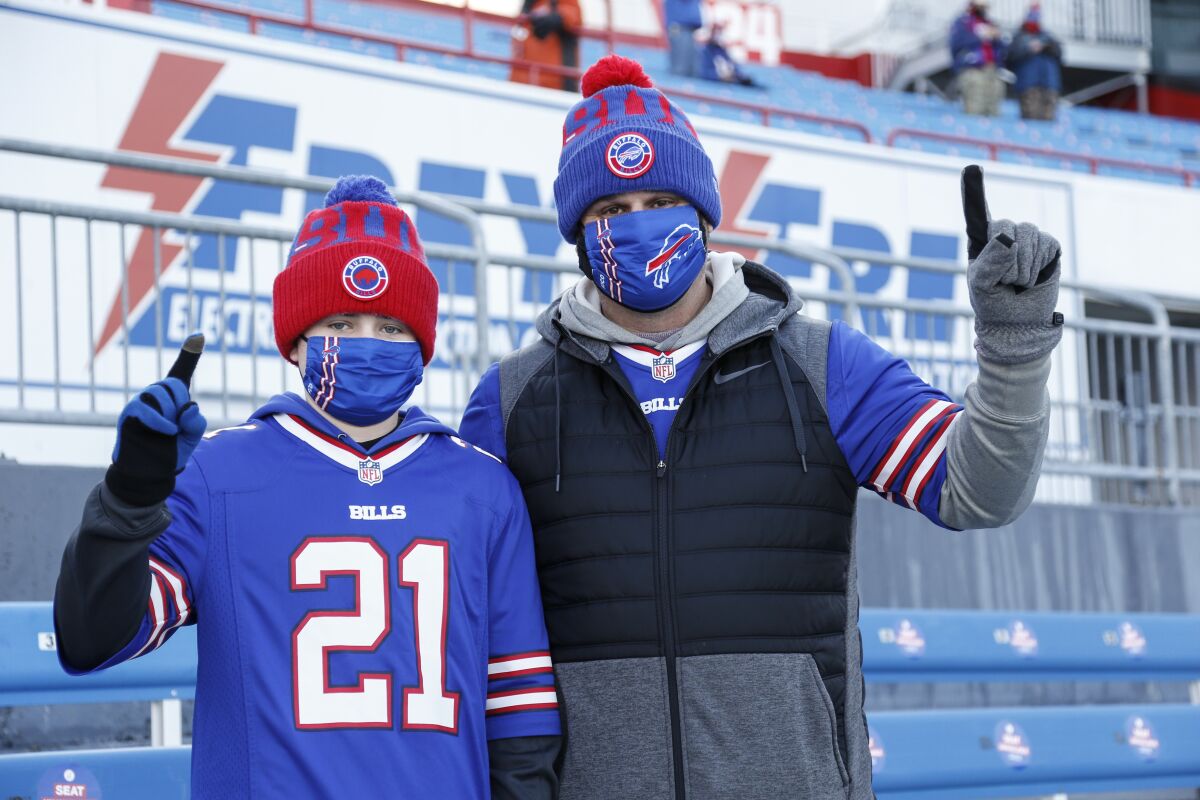 Buffalo Bills fans Scott Hammond, right, and his son Landon pose for a photograph as their team warms up before an NFL wild-card playoff football game against the Indianapolis Colts, Saturday, Jan. 9, 2021, in Orchard Park, N.Y. The Hammonds were among the lucky 6,700 few to land tickets for the Bills wild-card playoff against the Indianapolis Colts for Buffalo's first home playoff game in 24 years. (AP Photo/Jeffrey T. Barnes)