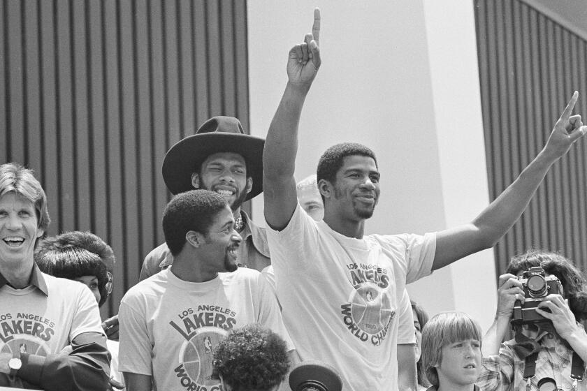 Los Angeles Lakers Earvin "Magic" Johnson, center, with arms raised, and teammates Norm Nixon, far left, Brad Holland and Kareem Abdul-Jabbar, wearing hat, respond to the crowd at a victory rally in Los Angeles, May 17, 1980. The Lakers beat the Philadelphia 76ers to win the NBA world championships, 4 games to 2, with Johnson selected as the series MVP. (AP Photo/Randy Rasmussen)