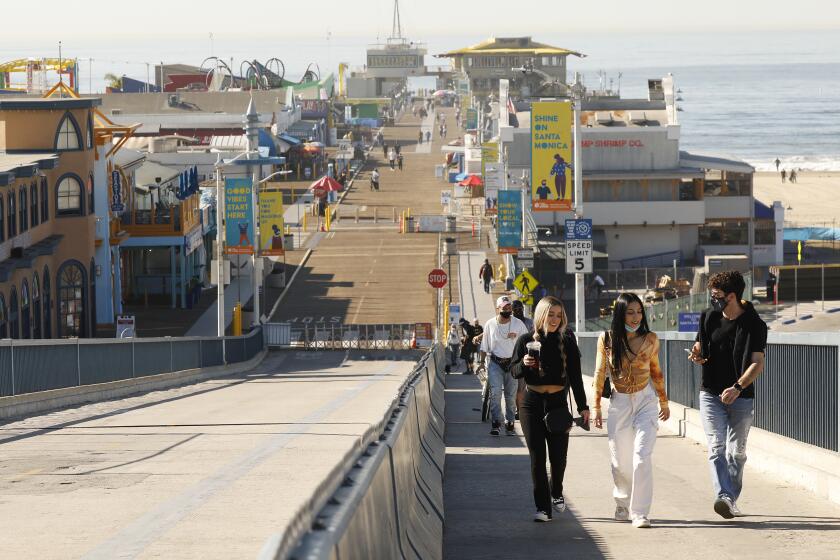 SANTA MONICA, CA - JANUARY 11: Pedestrians Monday morning enjoy the beautiful weather as they walk on the Santa Monica Pier. But out of an abundance of caution and to contribute to regional efforts to slow the spread of COVID-19 in Los Angeles County, the Santa Monica Pier will be temporarily closed the remaining weekends in January. The Pier remains open to pedestrians Monday Through Friday 6 a.m. to 10 p.m. The best way to slow the spread of COVID-19 is to stay home as much as possible and the closure is part of meeting this need. Santa Monica Pier on Monday, Jan. 11, 2021 in Santa Monica, CA. (Al Seib / Los Angeles Times)