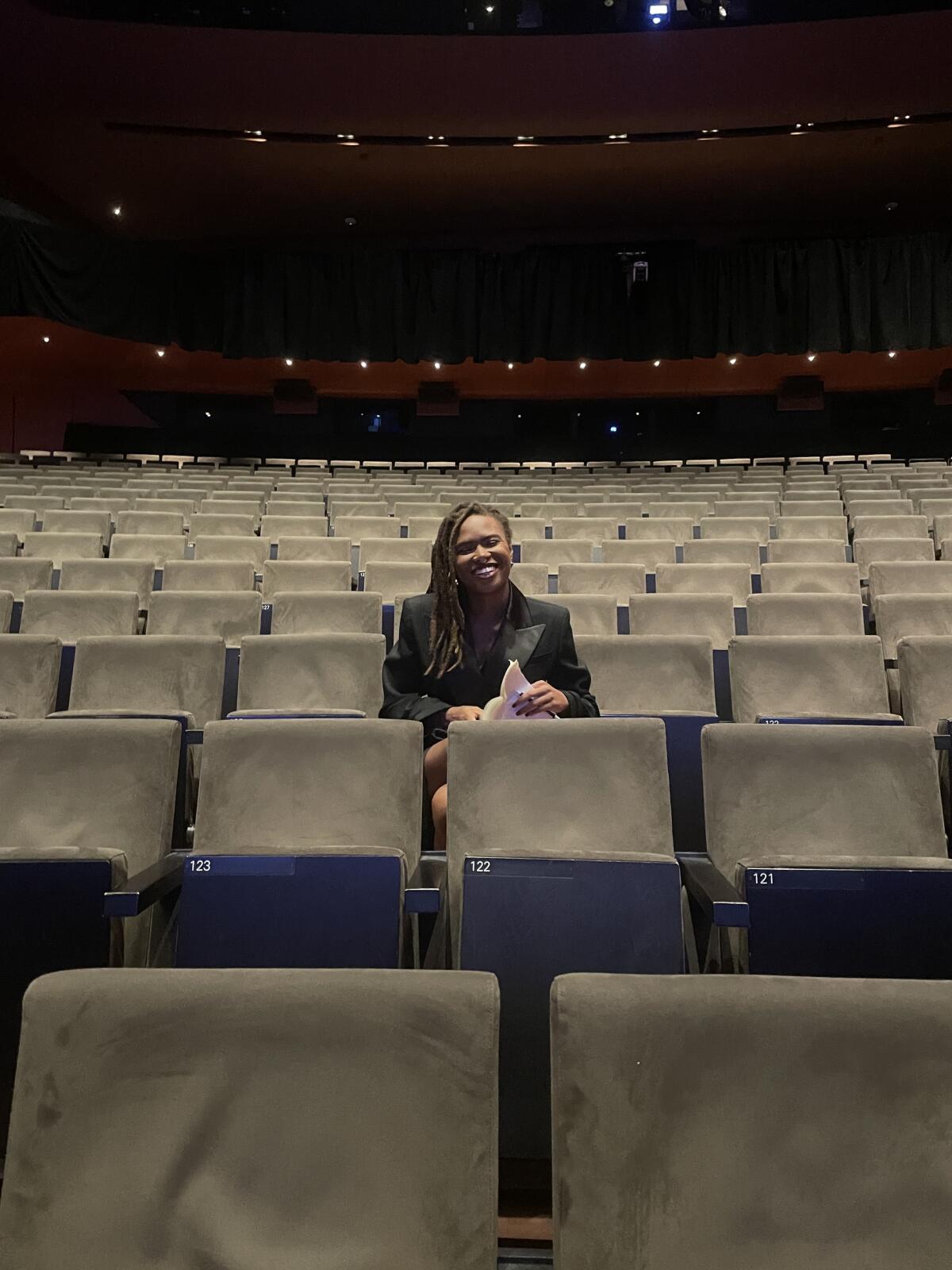 A person sitting along among rows of seats in a theater