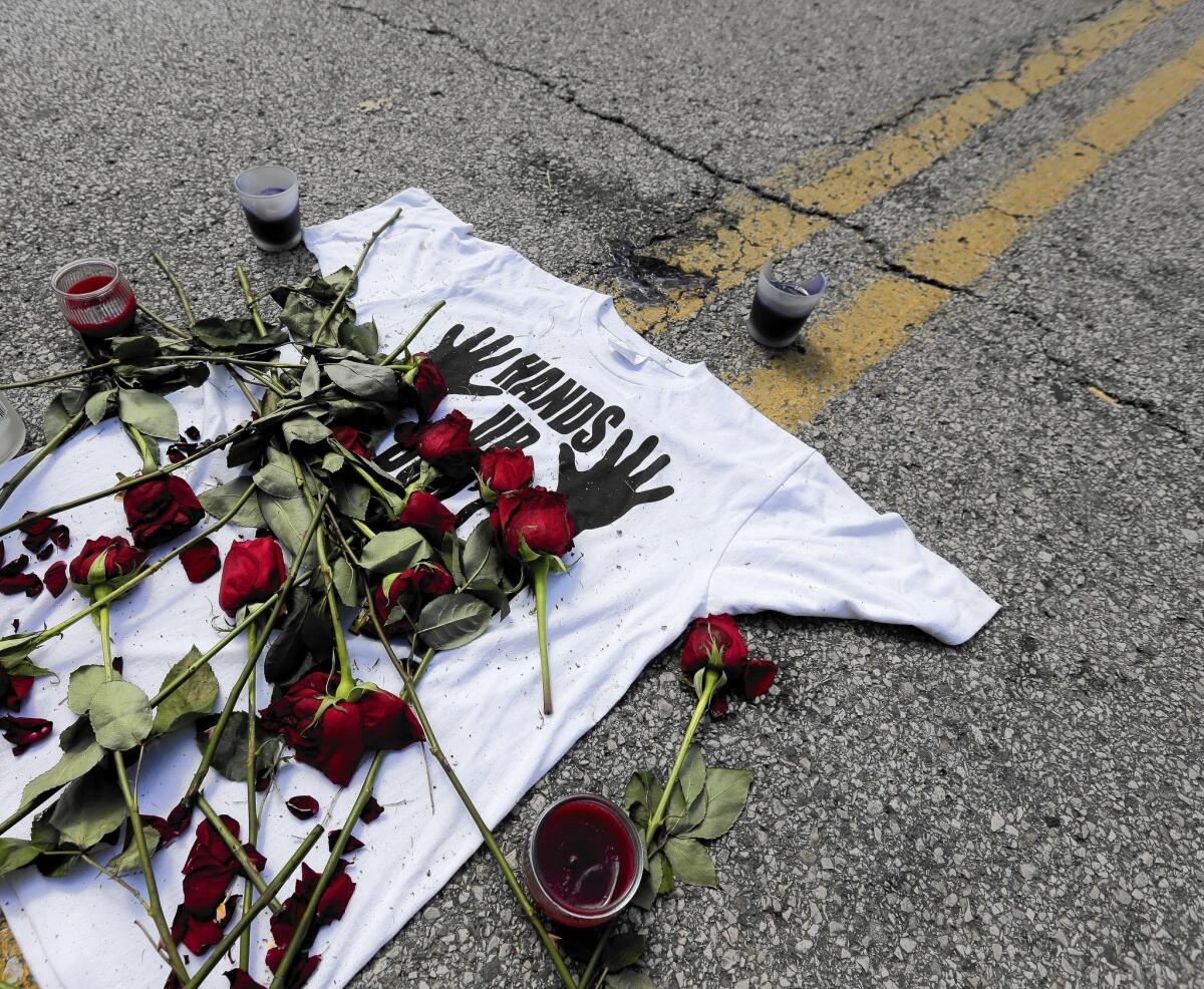 A shirt reading, "Hands up don't shoot," is covered with roses at the spot Michael Brown was killed by police.