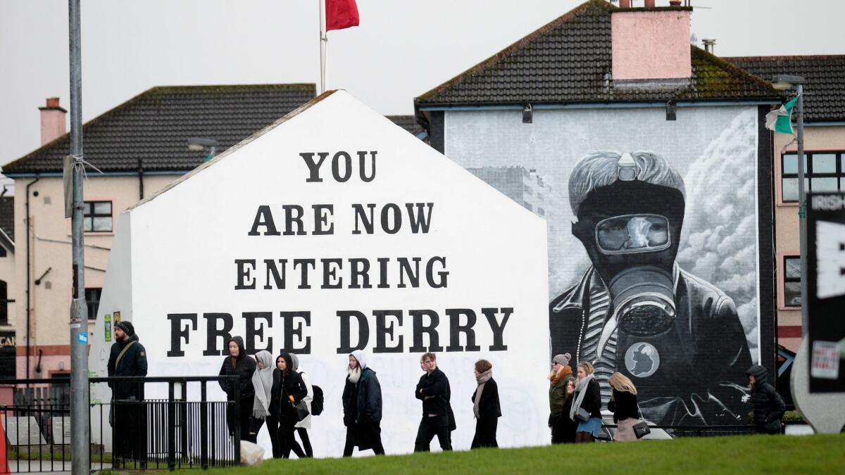 Tourists walk past a Republican mural in Londonderry, Northern Ireland, on Tuesday