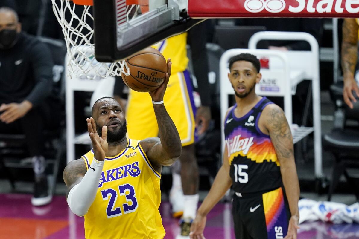 Lakers forward LeBron James scores in front of Phoenix Suns guard Cameron Payne during the Lakers' 109-102 victory.