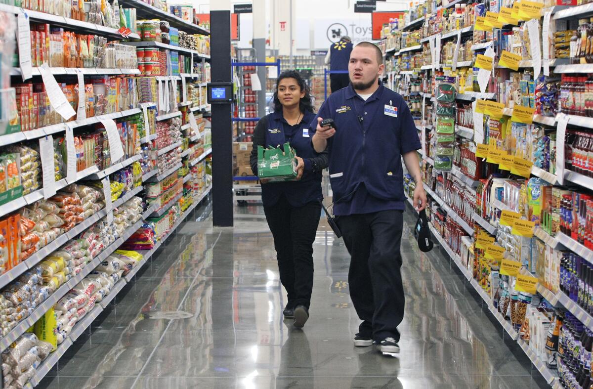 Cake decorator Deleyna Flores and product manager Rueben Estrada help stock shelves ahead of the Burbank Walmart Supercenter's grand opening.