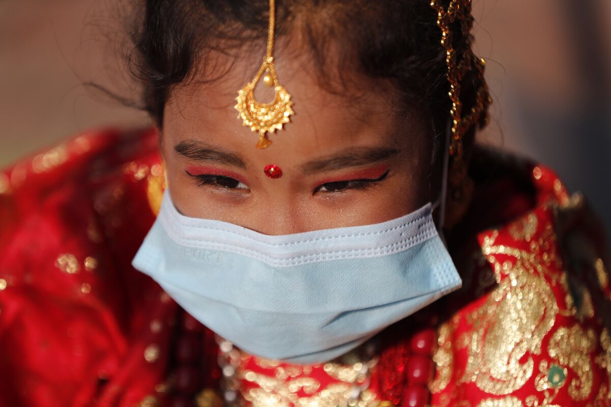 A young Newar girl waits for an Ihi ceremony in Kathmandu, Nepal, Friday, Dec. 4, 2020. Ihi is a two-day ceremony performed for girls who have not reached puberty and involves purification rituals and marriage rituals with the Bael (or wood apple). Newari girls are married thrice in their life, to the bael fruit and the sun before marrying a human. (AP Photo/Niranjan Shrestha)