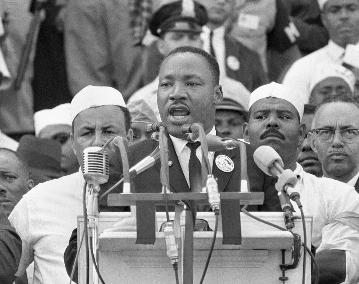 A black-and-white photo of the Rev. Martin Luther King Jr. addressing marchers at the Lincoln Memorial 
