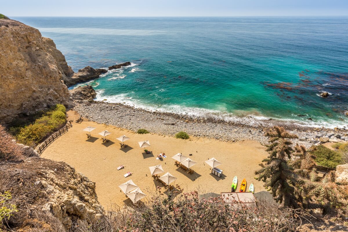 Beach umbrellas on the sand in a cove.