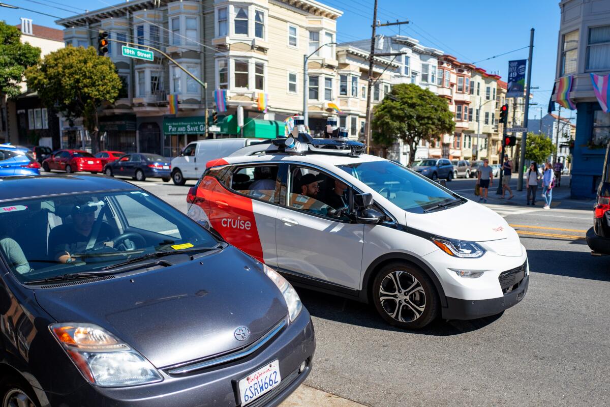 A self-driving car, with the Cruise logo, on a city street.