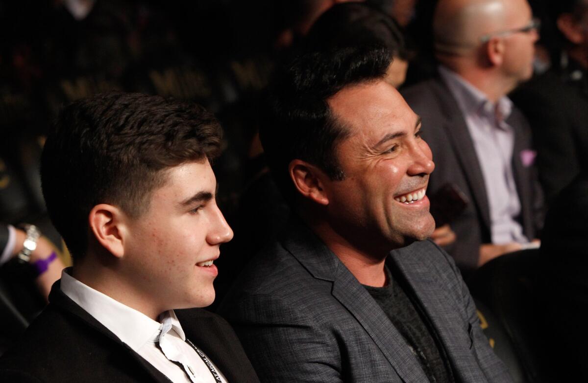 President of Golden Boy Promotions Oscar De La Hoya, right, sits with his son Devon at a boxing match on Jan. 17 in Las Vegas.