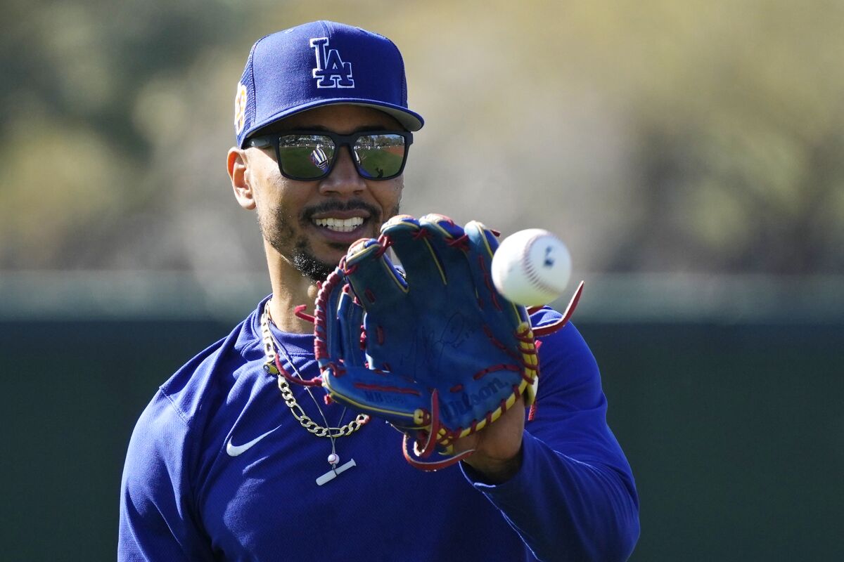 Dodgers right fielder Mookie Betts holds up his glove as a ball heads toward him.