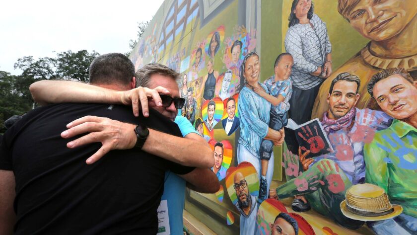 Artist Yuriy Karabash on Monday hugs a family member of a victim of the Pulse nightclub massacre in Orlando. Karabash's mural commemorates the one-year anniversary of the mass shooting that killed 49.