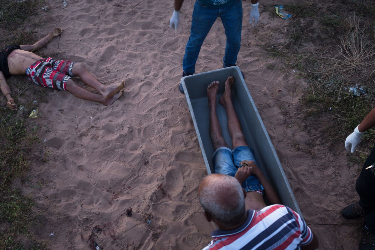 Police officers examine body of man murdered in a row between the criminal factions PCC and Crime Syndicate in the city of Natal, Brazil.
