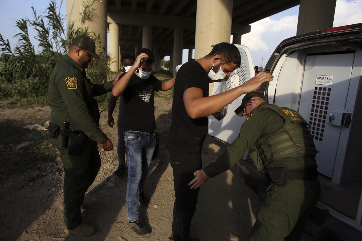 Agentes de la Patrulla Fronteriza de EEUU revisan a migrantes luego de que cruzaron el río Bravo hacia Estados Unidos 