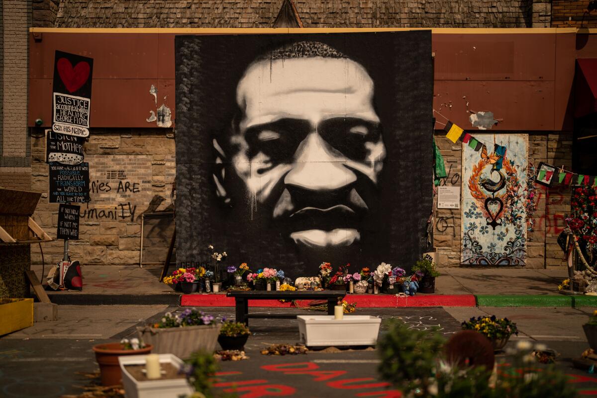 A black-and-white mural of George Floyd, with flowers placed around it, at George Floyd Square 