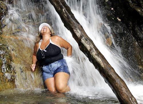 Debbie Rowlon of Sun City, a fugitive from triple-digit heat, enjoys a cool mountain waterfall Wednesday at Valley of the Falls near Redlands in the San Bernardino Mountains.