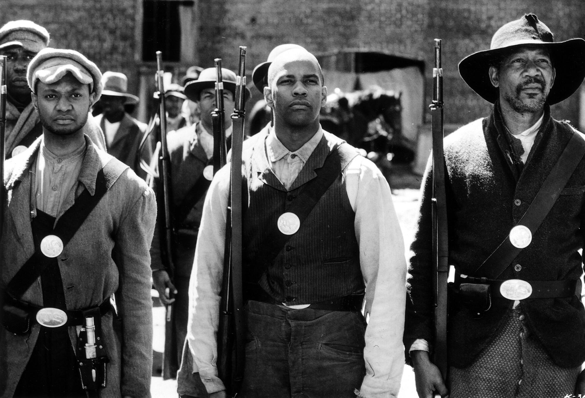 Denzel Washington, center, stands in uniform with a rifle next to Morgan Freeman  in "Glory" 