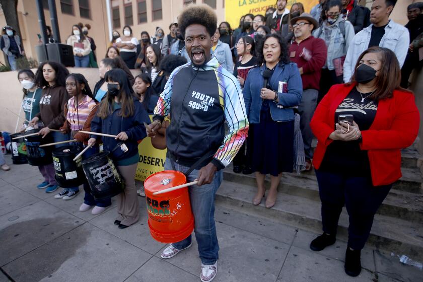 LOS ANGELES, CALIF. - JAN. 31 2023. Dr. Amir Whitaker, center, leads a drum line during a press conference on Tuesday, Jan. 31, 2023, to announce the release of the Police Free LAUSD Coalition's report titled, "From Criminalization to Education: A Community Vision for Safe Schools in LAUSD." Dozens gathered outside Mann UCLA Community School in South L.A. for the announcement. (Luis Sinco / Los Angeles Times)