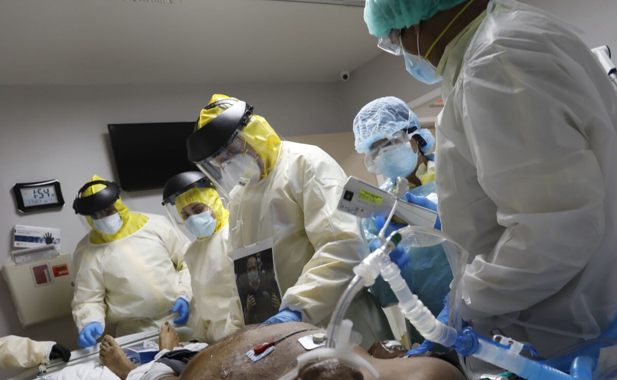 Hospital workers in protective gear surround a patient