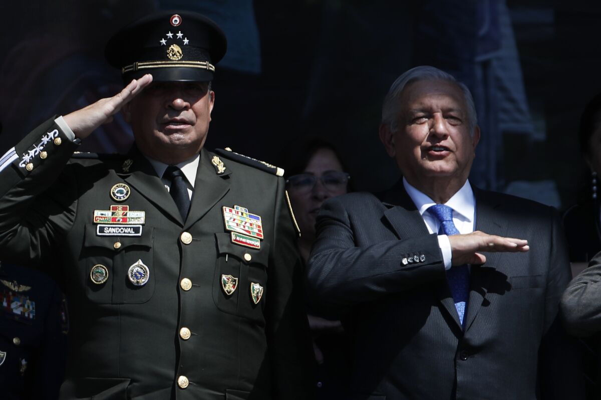 Mexico's Defense Secretary Luis Cresencio Sandoval and Mexico's President Andres Manuel Lopez Obrador salute during an event.